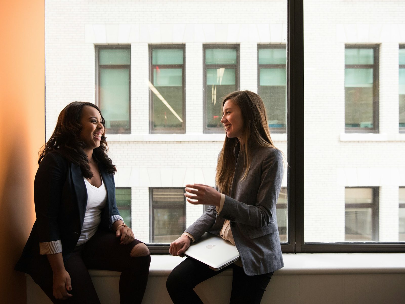 Two colleagues talking warmly by a window.